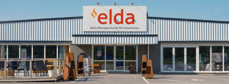 Fasad av en Eldabutiken med stort skylt och utomhusutställning med stolar och eldstäder. Butiken marknadsför brasvärmeprodukter.