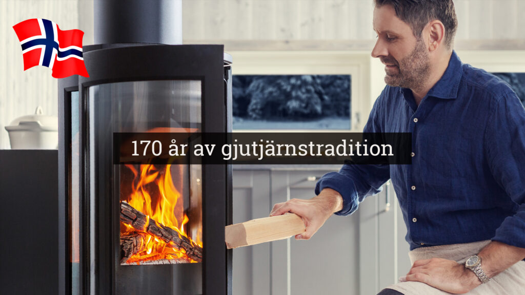 Man matar en eldstad med ved, texten "170 år av gjutjärnstradition" syns. Norsk flagga i bakgrunden.