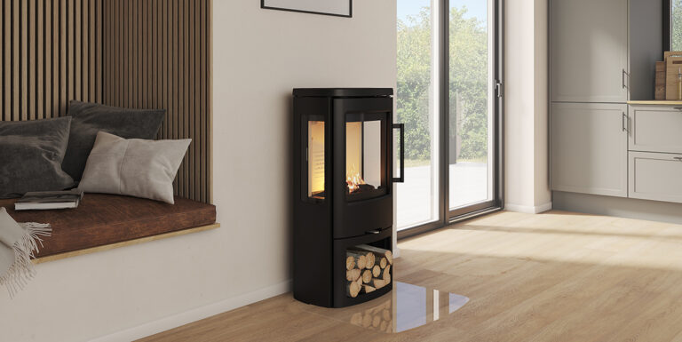 Modern kamin i ett ljust vardagsrum, med vedförvaring under och eld synlig genom glasluckor. Vardagsrummet har stora fönster och en sittplats med kuddar.