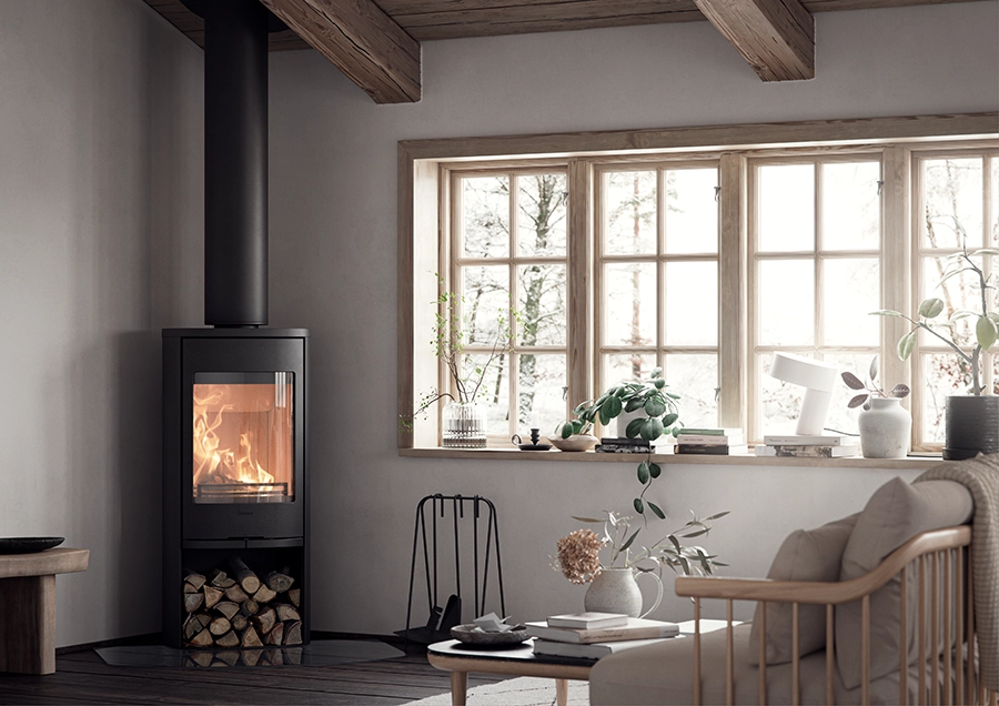 Modernt vardagsrum med braskamin, vedförvaring och stora fönster som släpper in naturligt ljus. Stilren inredning med växter och dekorativa föremål på fönsterbrädan.