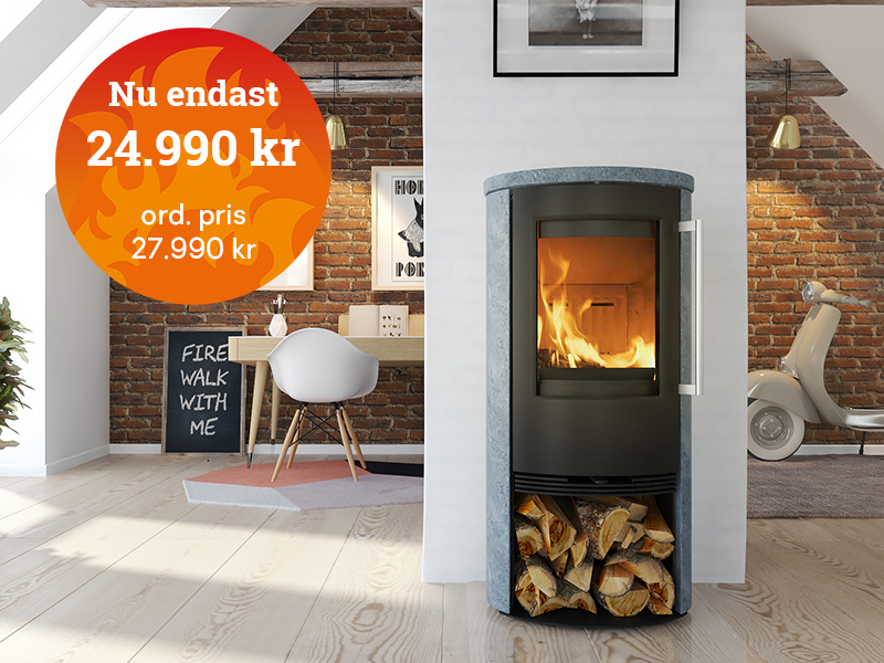 Modern kamin i vardagsrumsmiljö med tegelvägg, prisskylt 24.990 kr. Kamin med vedförvaring under, omgiven av inredningsdetaljer och motorcykel.