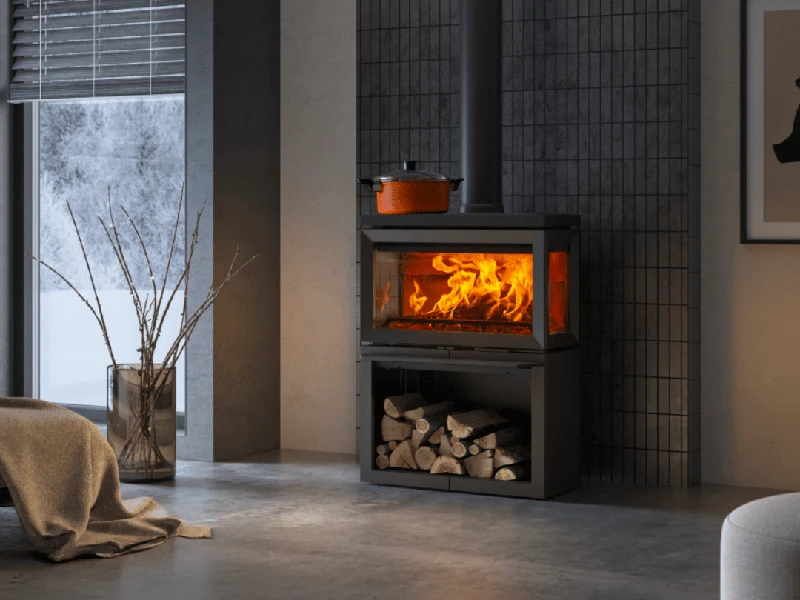 Modern kamin med eld, vedförvaring och orange gryta i stilrent vardagsrum. Fönster med vinterutsikt och dekorativ vas med grenar.