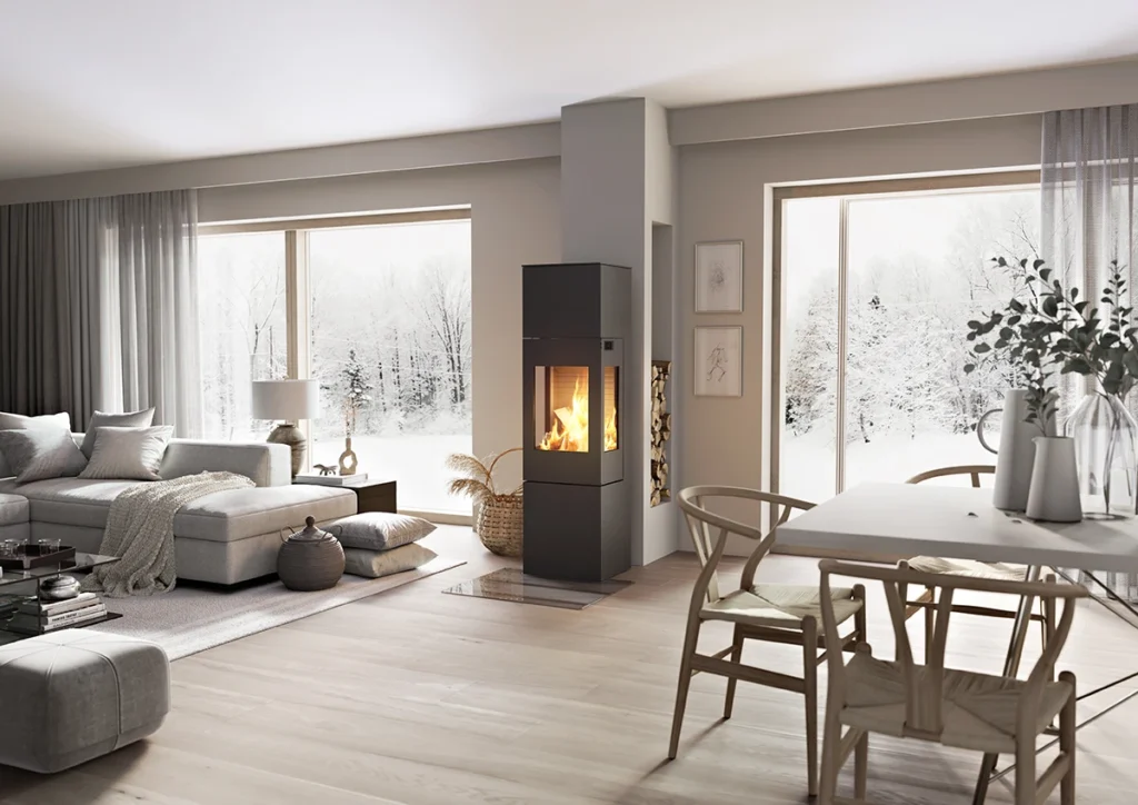 Modern vardagsrum med eldstad och stora fönster som visar snöigt landskap utanför. Ljus inredning med grå soffa och träbord.