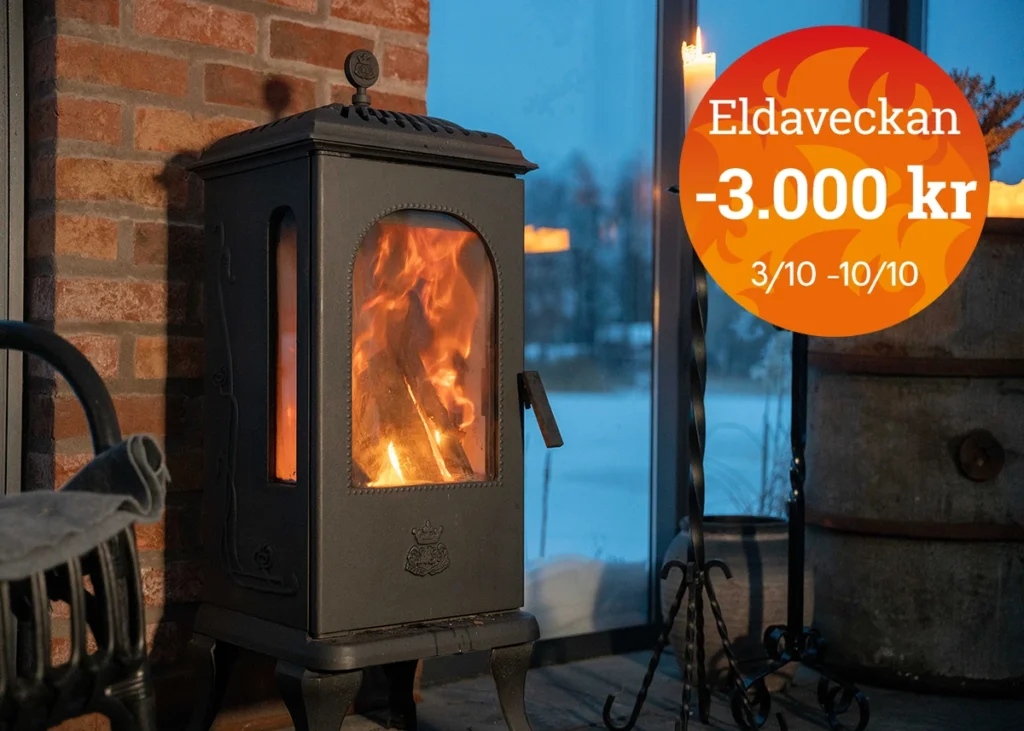 Vedeldad kamin med eld, placerad vid en tegelvägg och glasfönster. Kampanjtext "Eldaveckan -3.000 kr 3/10 - 10/10" i en orange cirkel.